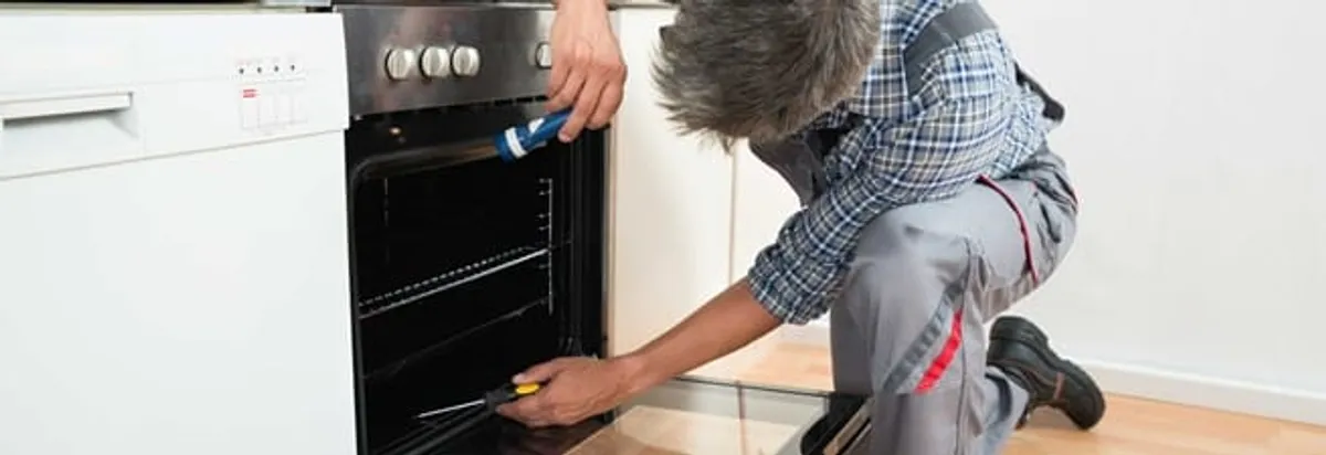 Oven repair technician inspecting and servicing an electric oven in Charleston, SC
