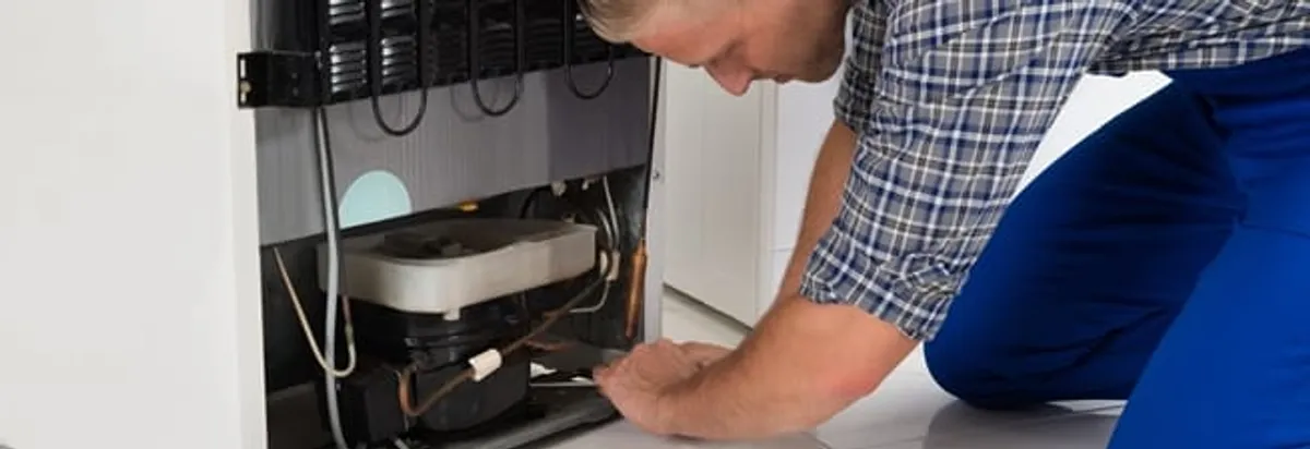 Refrigerator repair technician servicing the compressor and condenser area in Charleston, SC