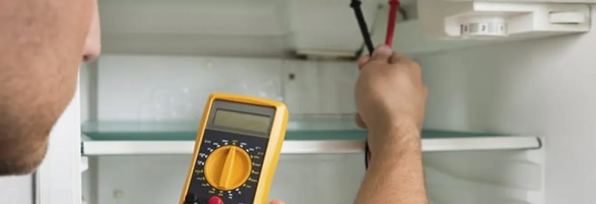 Refrigerator repair technician testing electrical components with a multimeter in Charleston, SC